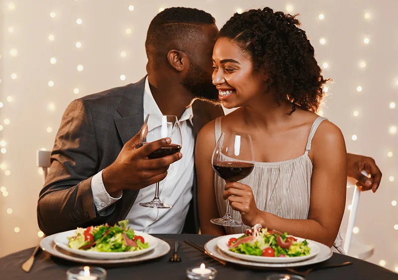 A couple at dinner under strings of warm lights